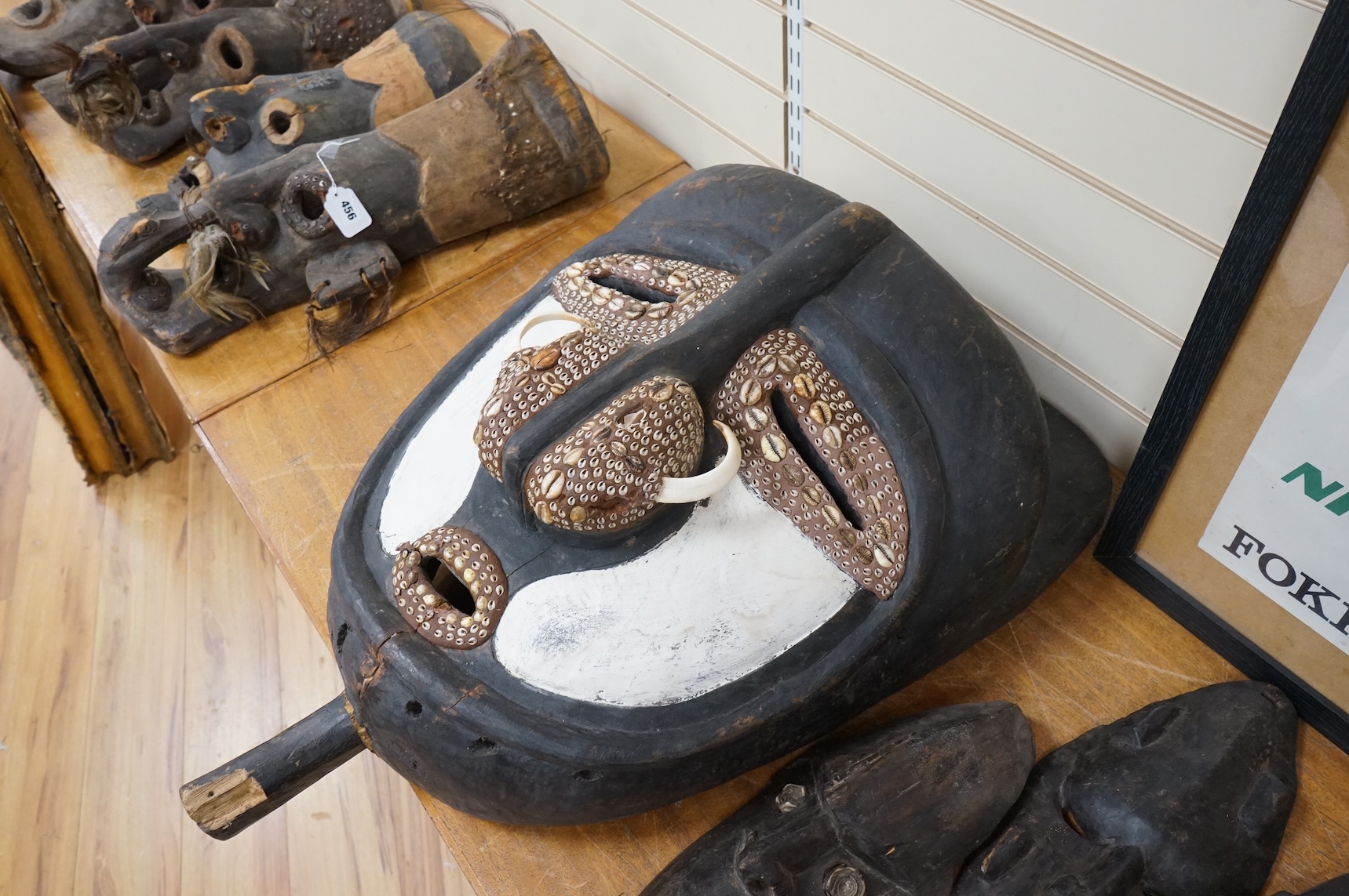 A Papua New Guinea Sepik River large carved wooden mask, painted in black and white and applied with pig tusks and teeth, together with five small plain masks, largest 82cm high